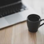 black ceramic mug beside macbook pro