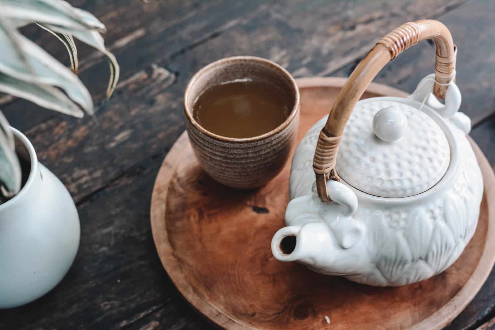 white and brown ceramic teapot on wooden tray