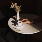 person holding white ceramic mug on white round table